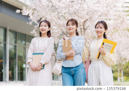 Three female college students walking on a cherry blossom campus 135379186