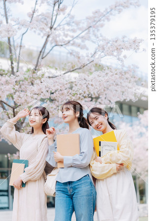 三位女大學生漫步在櫻花盛開的校園裡。 135379195