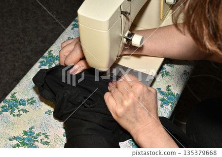 The seamstress works at the sewing machine. The seamstress works at the sewing machine. 135379668