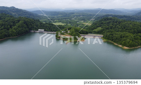Aerial view of the dam lake, dam body, and green mountains 135379694
