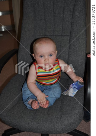 Cute Baby Sitting on a Chair Holding a Paper Cute Baby Sitting on a Chair Holding a Paper 135379721