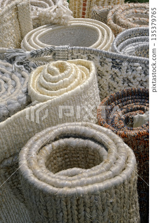 Group of assorted carpets and rugs of various sizes and colors, rolled 135379765