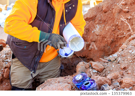 Workers are installing plumbing drainage pipes in various pipe layouts at trench construction area 135379963