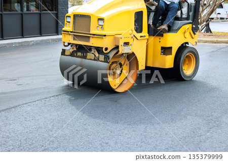 Yellow steamroller machine is flattening fresh asphalt at construction site Yellow steamroller machine is flattening fresh asphalt at construction site 135379999