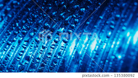 Wet texture. Stripe glow defocused. White lines luminosity on blue background. Color water drops on abstract ribbed glass surface. 135380092