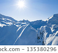 Freeride skier standing on a snowy mountain ridge, preparing for descent in pristine alpine terrain. Bright winter sun, dramatic peaks and untouched snow create a powerful adventure atmosphere. 135380296