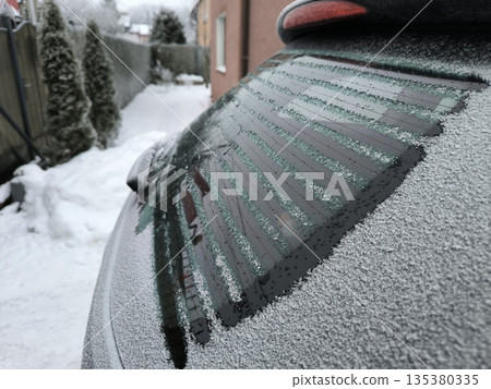 The rear window of the car is heated and defrosted from frost, side view 135380335