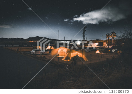 A campsite at night with lit tents under the starry sky 135380570