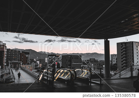 Evening view of the station deck and escalator, and the cityscape with mountain views Evening view of the station deck and escalator, and the cityscape with mountain views 135380578