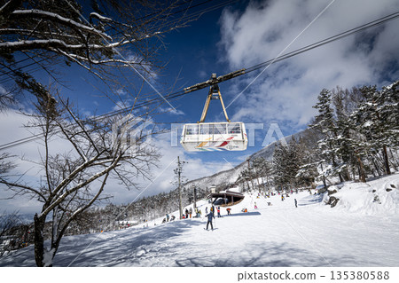 纜車穿梭於藍天白雲和熙熙攘攘的滑雪道之間 纜車穿梭於藍天白雲和熙熙攘攘的滑雪道之間 135380588