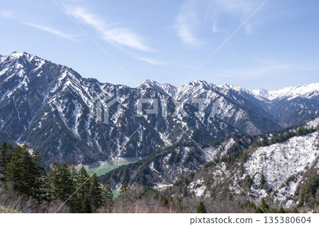 Snow-capped mountains and an emerald lake in a valley 135380604