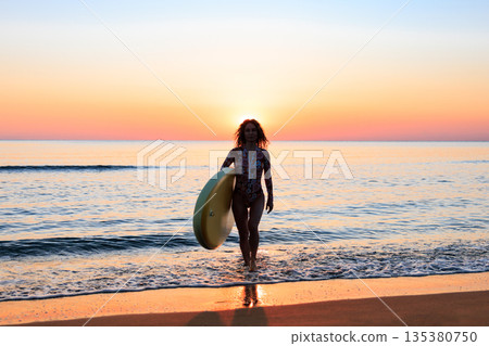 Young woman standing on beach with paddle sup boards during summer vacation Young woman standing on beach with paddle sup boards during summer vacation 135380750