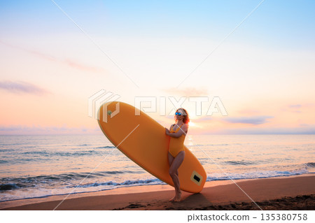 Young woman walking on stand up paddle sup boards by the sea during summer vacation 135380758