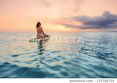 Young woman walking on stand up paddle sup boards by the sea during summer vacation Young woman walking on stand up paddle sup boards by the sea during summer vacation 135380759