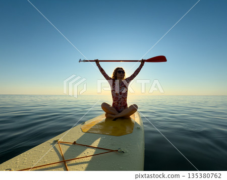 Young woman walking on stand up paddle sup boards by the sea during summer vacation 135380762
