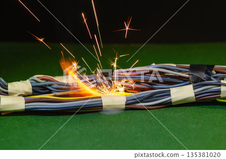 Bright electric sparks inside the bundle of wires indicate a dangerous malfunction of the electrical network. Bright electric sparks inside the bundle of wires indicate a dangerous malfunction of the electrical network. 135381020