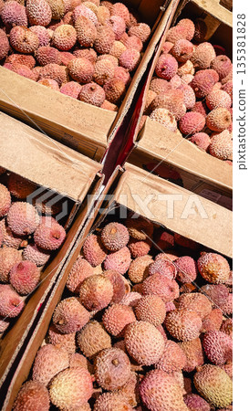 Fresh ripe lychee fruits packed in cardboard boxes for sale at a local wholesale market or grocery. Fresh ripe lychee fruits packed in cardboard boxes for sale at a local wholesale market or grocery. 135381828