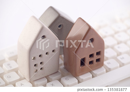 Group of three different houses on white computer keyboard 135381877