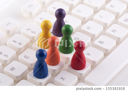 Colorful group of pawn people figures on computer keyboard Colorful group of pawn people figures on computer keyboard 135381910