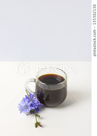Glass cup with chicory drink and blue chicory flowers on gray background. Healthy eating 135382138