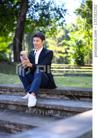 Office man connecting on phone while holding a coffee cup outdoors 135382202