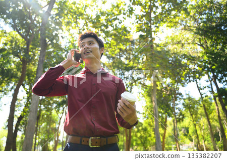 Man talking on phone in a bright green park 135382207
