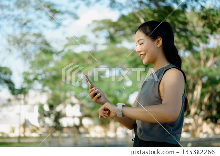 Women pausing during run, checking fitness progress in smartphone Women pausing during run, checking fitness progress in smartphone 135382266