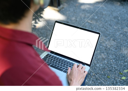 Cropped shot man using empty display laptop in the park with clipping path 135382334
