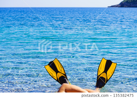 Feet in flippers fins on sea shore Feet in flippers fins on sea shore 135382475