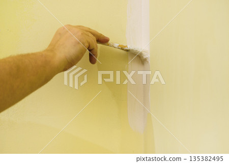 Person applying paint on wall 135382495