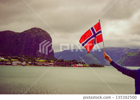 Tourist with norwegian flag on fjord Tourist with norwegian flag on fjord 135382500