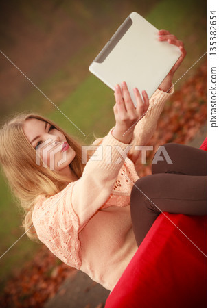 Girl sitting on bench with tablet. 135382654