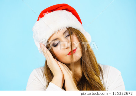 Woman in santa hat being sleepy Woman in santa hat being sleepy 135382672