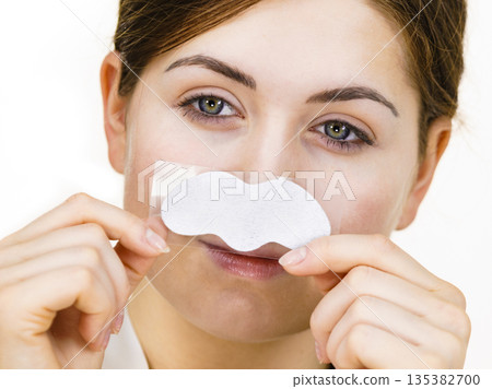 Woman applying pore strips on nose Woman applying pore strips on nose 135382700