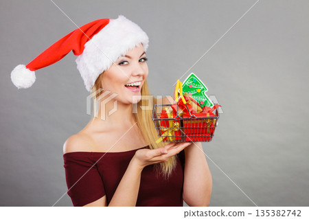 Santa woman holding shopping cart with christmas gifts 135382742