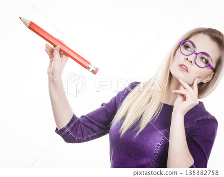 Woman confused thinking, big pencil in hand Woman confused thinking, big pencil in hand 135382758