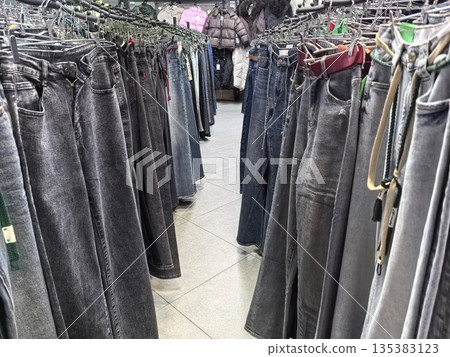 Variety of denim jeans hanging in a busy clothing store aisle Variety of denim jeans hanging in a busy clothing store aisle 135383123