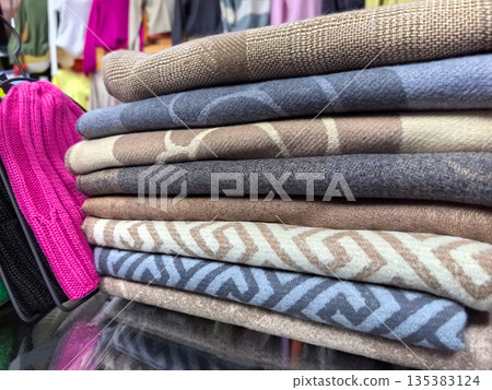 Colorful textiles display in a vibrant market stall during sunny afternoon Colorful textiles display in a vibrant market stall during sunny afternoon 135383124