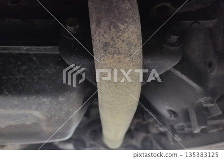Exhaust pipe under a vehicle reveals signs of wear and tear 135383125
