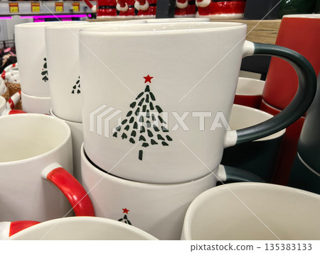 Festive mugs display featuring cheerful Christmas tree designs in store Festive mugs display featuring cheerful Christmas tree designs in store 135383133
