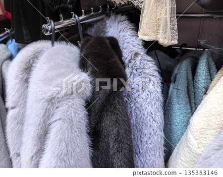 Charming collection of cozy cloth textures in soft hues hanging in a boutique 135383146