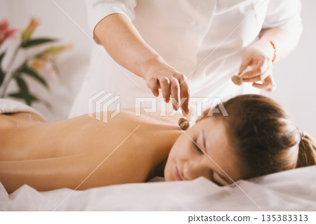 Young beautiful woman in spa receiving procedure of tibetan medicine 135383313