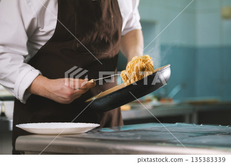 Chef serves spaghetti on the plate Chef serves spaghetti on the plate 135383339
