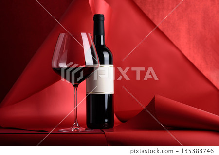 Red Wine Bottle and Glass on Red Background. Elegant Festive Still Life 135383746
