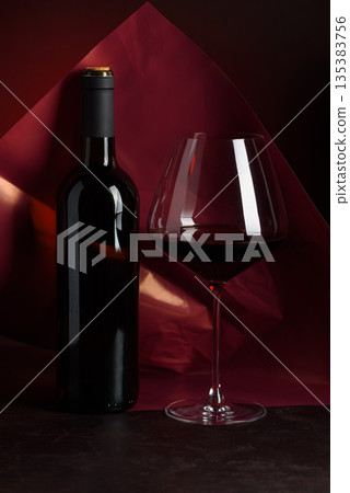 Red Wine Bottle and Glass on Dark Red Gradient Background. Elegant Still Life Red Wine Bottle and Glass on Dark Red Gradient Background. Elegant Still Life 135383756