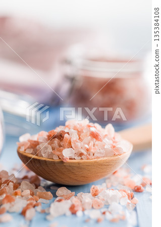 Pink Himalayan salt on wooden spoon on blue table. 135384108