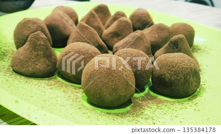 A plate of chocolate covered balls with a green background 135384178