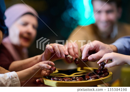 Muslim family sharing iftar in a restaurant with Ramadan decorations and warm lighting Muslim family sharing iftar in a restaurant with Ramadan decorations and warm lighting 135384198