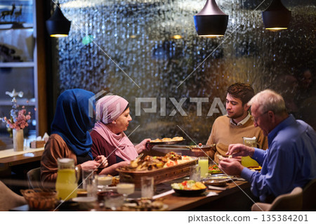 Family enjoys iftar in a restaurant during Ramadan with decorations and warm lighting 135384201