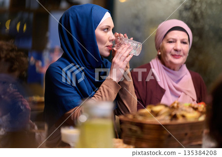 Muslim family breaking fast during Ramadan in a restaurant setting with traditional decorations 135384208